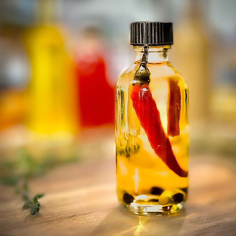 Bottle of hot sauce with a red pepper inside on a wooden surface