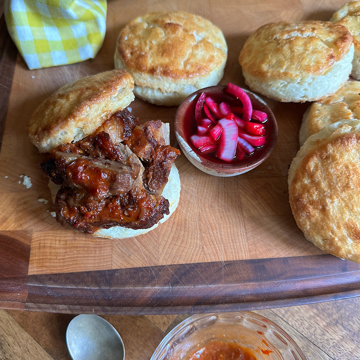 Biscuit sandwich with pork and pickled red onions on a wooden board