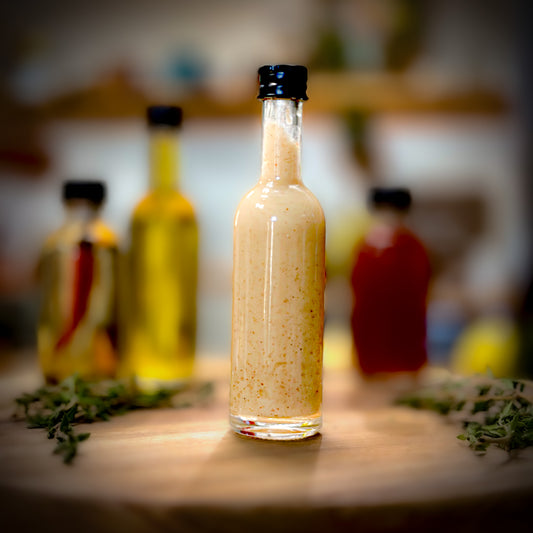 Glass bottle of salad dressing on a wooden surface with blurred background